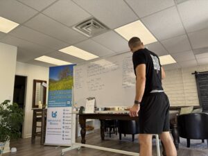 Movement coach Brian writing out a customized functional strength workout routine on a whiteboard during a fitness class at BeFit.